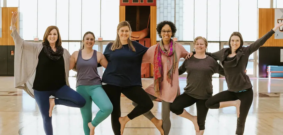 Six teachers in tree pose in a school gym